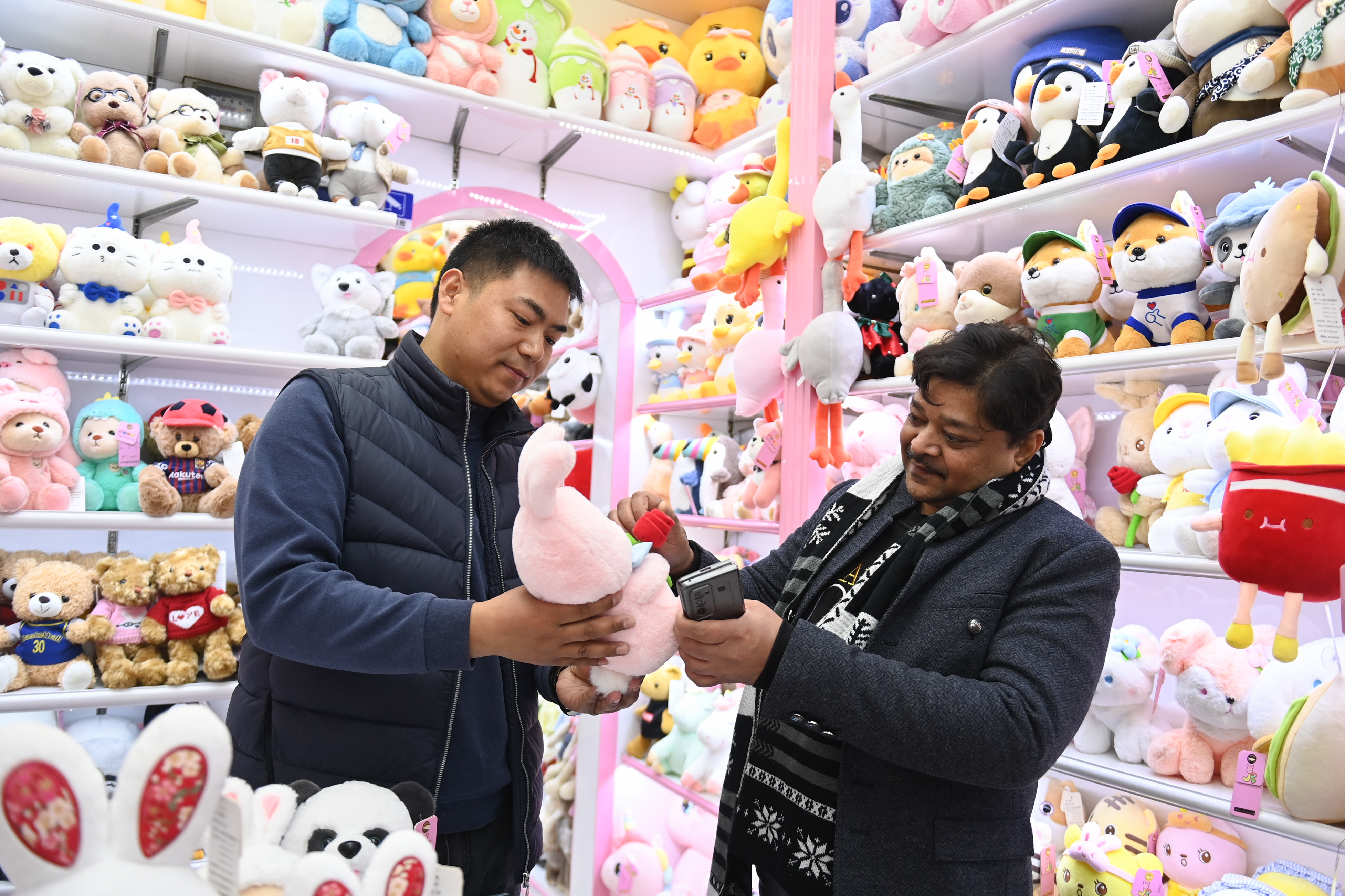 2023年2月2日，來(lái)自印度的客商（右）在義烏國際商貿城的一家玩具店鋪內選購。
